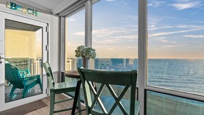 Varanda com vista para o oceano, uma mesa com cadeiras e uma placa que diz 'TO THE BEACH'.