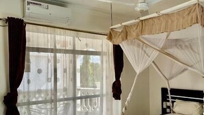 Una stanza con un letto, una ventola a soffitto e una finestra con tende.