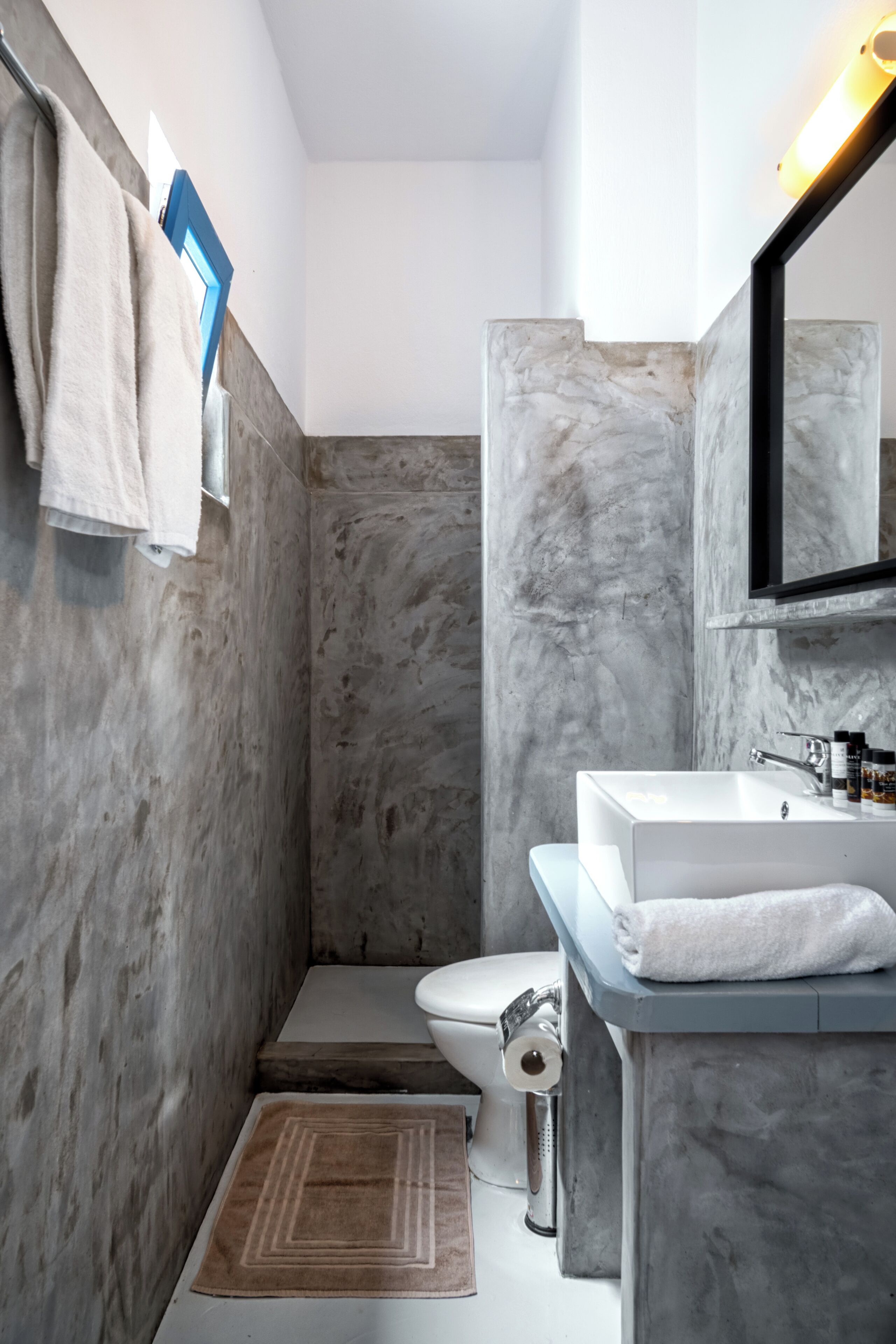 A bathroom with a marble wall, a white sink, and a toilet.