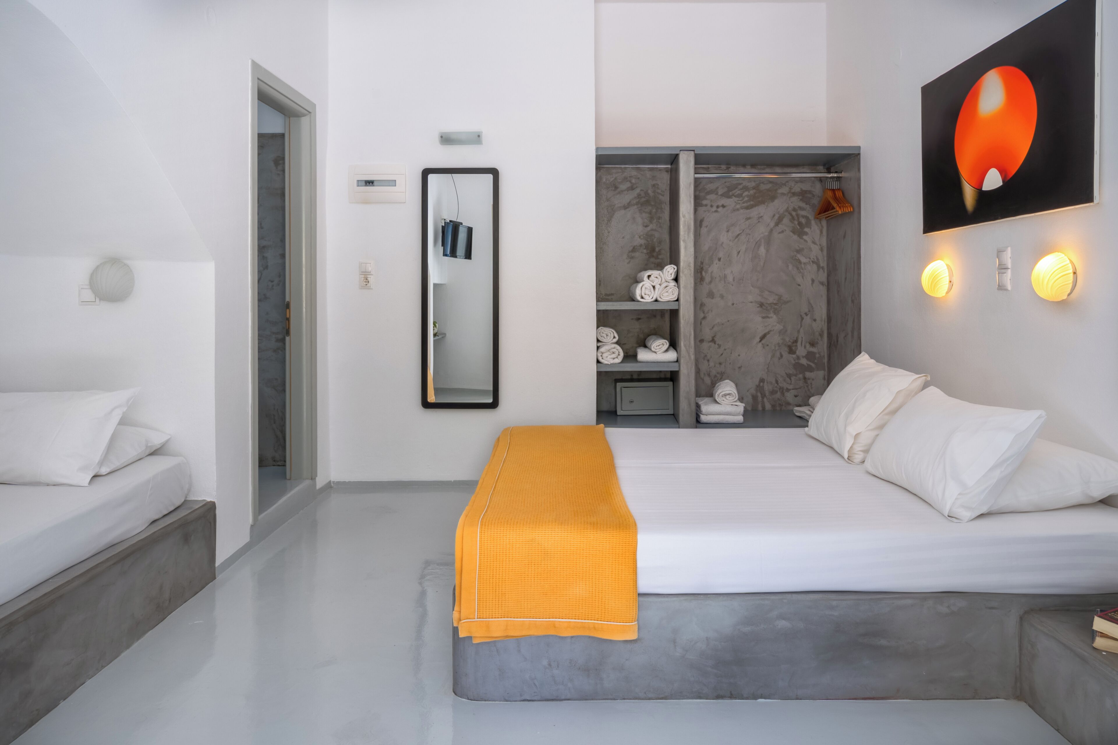 Een moderne slaapkamer met een groot bed, een bankje, een kledingkast en een badkamer die door een open deur zichtbaar is.