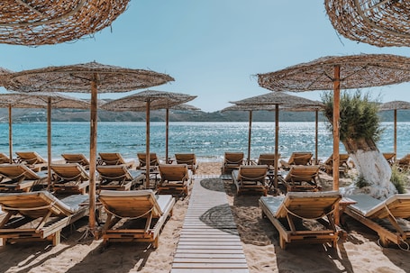 En la playa, playa de arena blanca, camastros y sombrillas