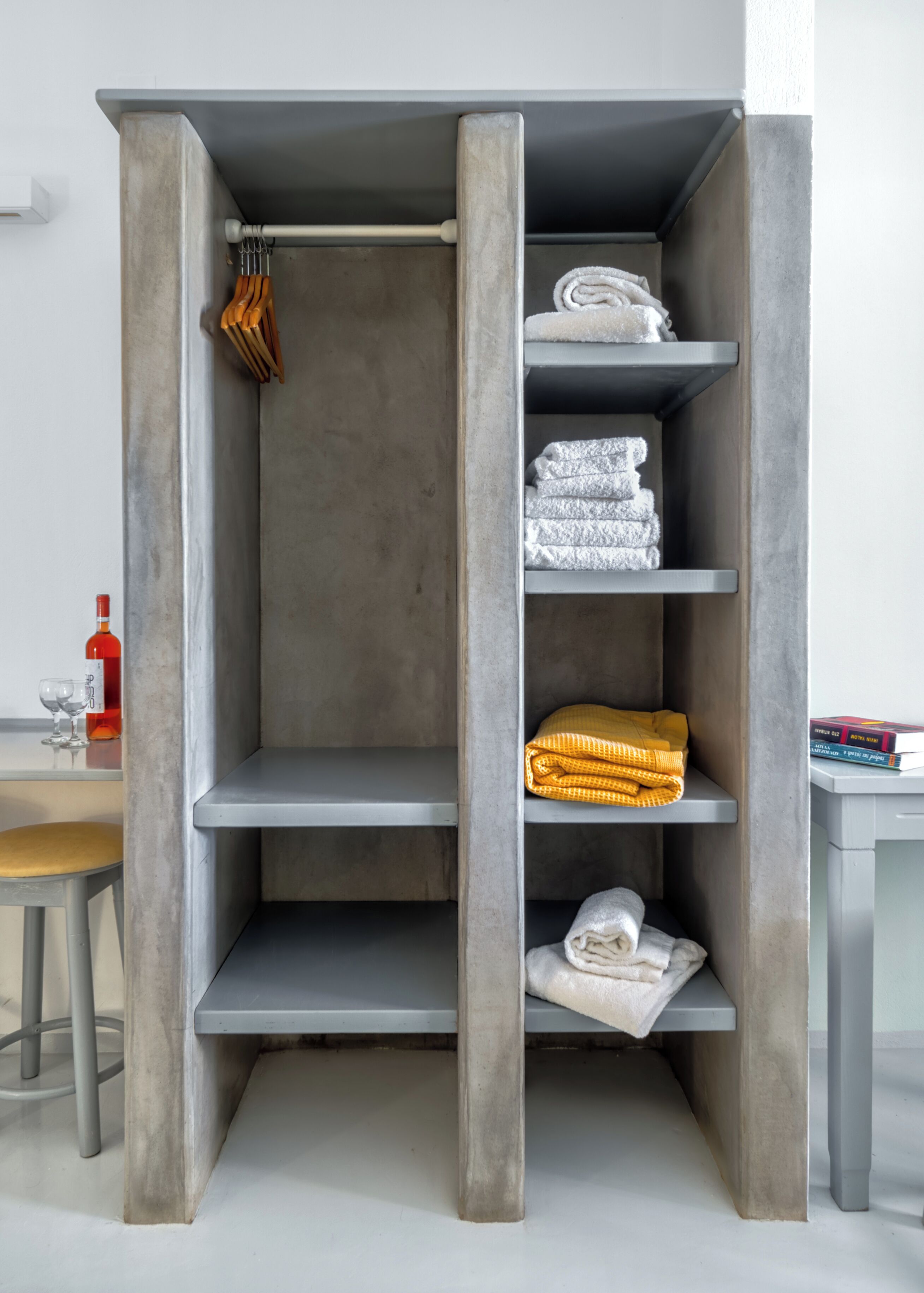 A modern, minimalist wardrobe with grey shelves and a central hanging rod.