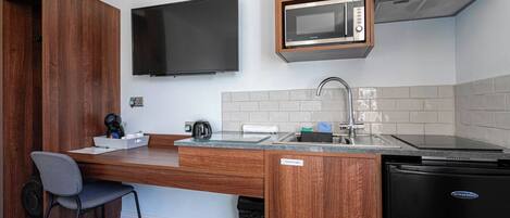 A compact kitchenette with a microwave, sink, and a small refrigerator.