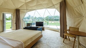 A spacious tented room with a bed, a television, and a table. - Bubble Glamping King Bed, we Have a 8 Units Like This! (Sosúa)