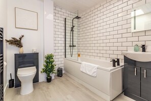 Une salle de bain moderne avec une baignoire blanche, des toilettes et un lavabo.