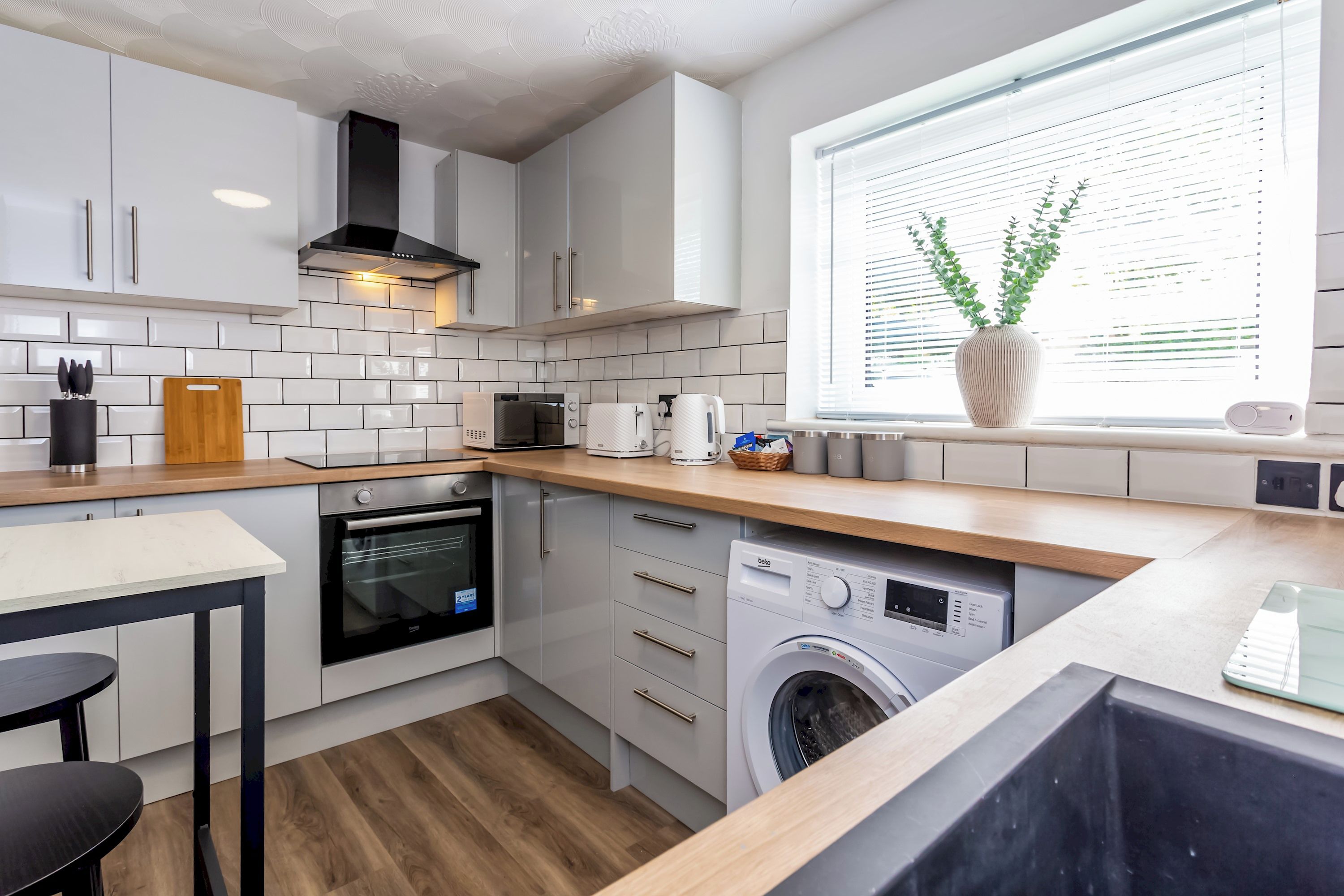 A compact kitchen with white cabinets, a microwave, a toaster, and a built-in washing machine.