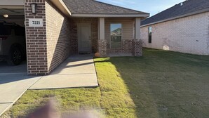 A residential building with a garage, brick exterior, and a well-maintained lawn. - Beautiful brand new home. Just entered VRBO market November 6.  All things new! (Lubbock)