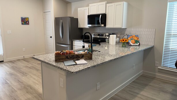 A modern kitchen with white cabinets, stainless steel appliances, and a granite countertop. - Beautiful brand new home. Just entered VRBO market November 6.  All things new! (Lubbock)