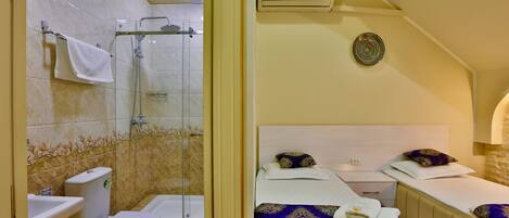 A bathroom with a glass shower enclosure, a toilet, and a sink.