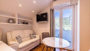 A modern living room with a white sofa, a round table, and a TV mounted on the wall. - Stay @ Bolotel studio SAVE 20 percent on Zlatnirat-bol com (Bol)