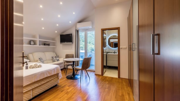 A modern bedroom with a bed, a TV, a dining area, and a view of the outdoors. - Stay @ Bolotel studio SAVE 20 percent on Zlatnirat-bol com (Bol)