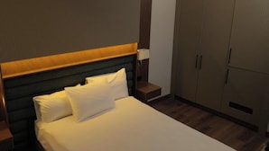 Une chambre d’hôtel avec un lit, une table de chevet, une lampe et une armoire.