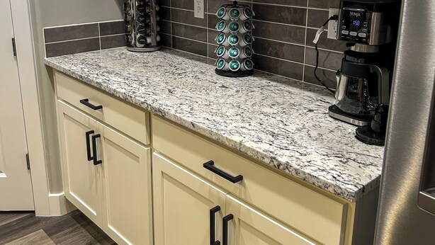 A kitchen with white cabinets, a granite countertop, and a stainless steel refrigerator. - Game Room • New Construction • 5 Bedrooms, 2 Baths (Mesquite)