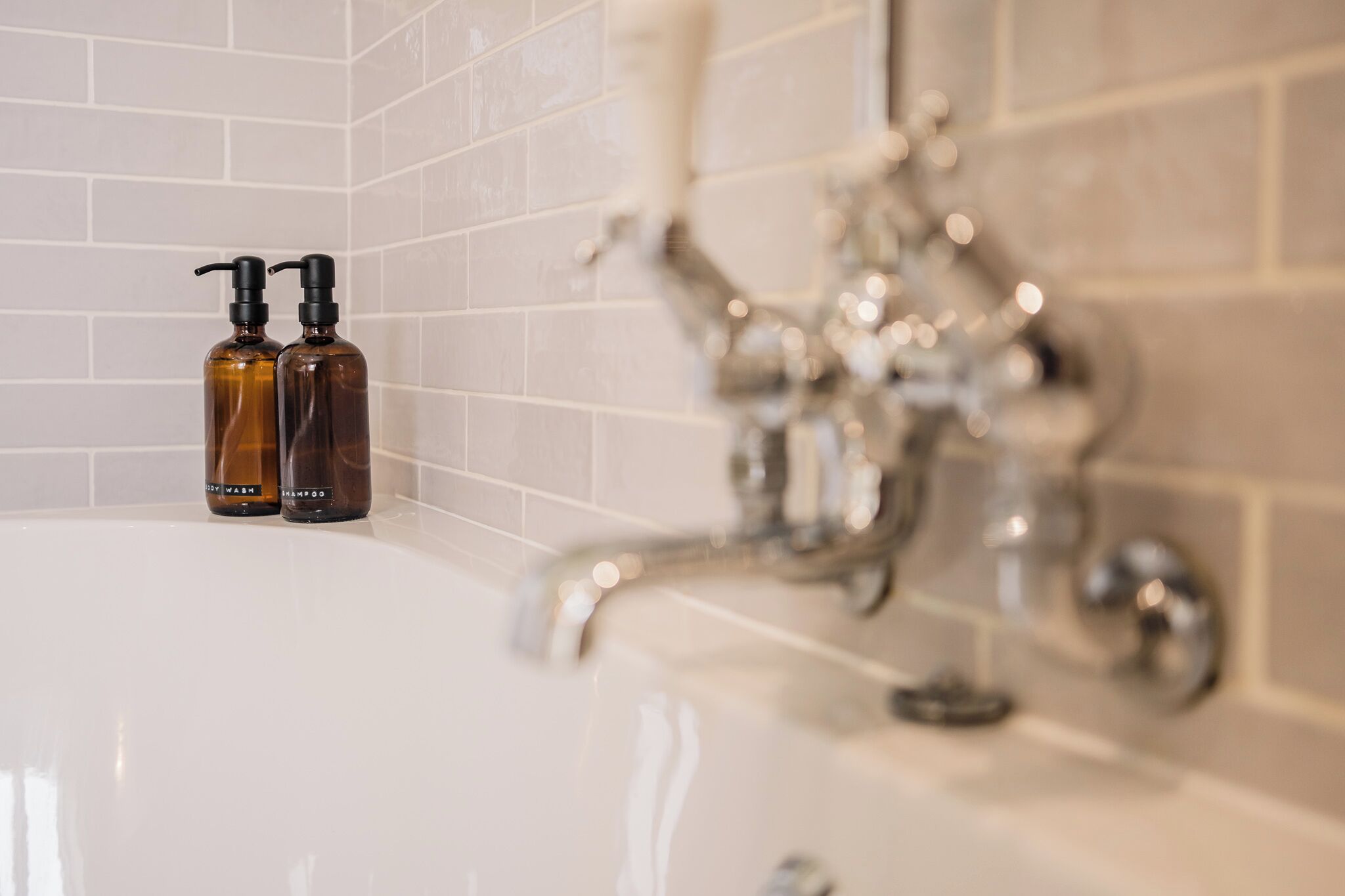 Une salle de bain avec une baignoire, deux bouteilles de shampoing et un robinet.