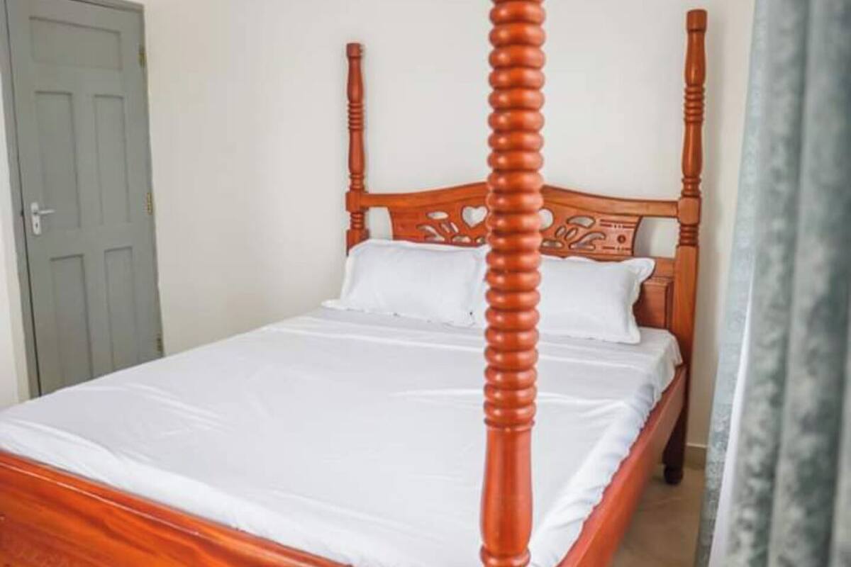 A four-poster bed with a wooden frame and white bedding.