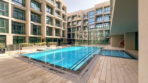Ein modernes Hotel mit großem Außenpool, mehreren Balkonen und einem gepflegten Garten.