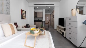 Ein modernes Hotelzimmer mit Bett, Fernseher, Kommode und einem Essbereich mit Tisch und Stühlen.