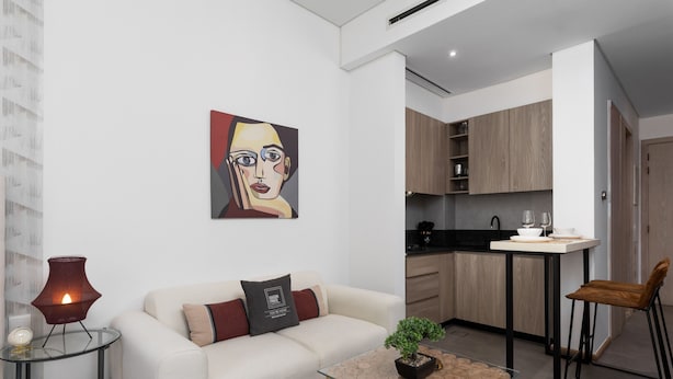 Ein modernes Wohnzimmer mit einer Couch, einem Glastisch und einem Gemälde an der Wand.
