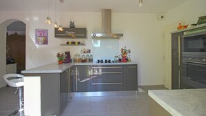 Una cocina moderna con una isla central, electrodomésticos de acero inoxidable e iluminación colgante.