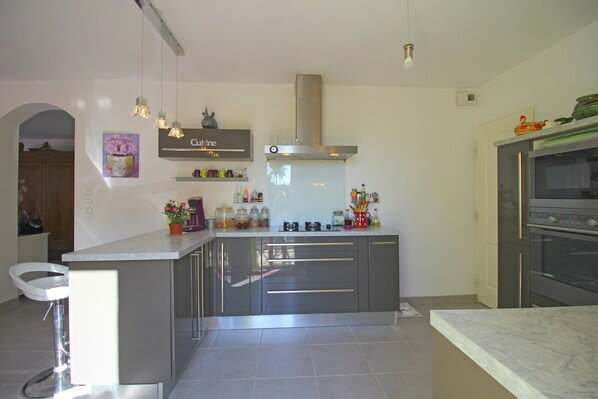 A modern kitchen with a central island, stainless steel appliances, and pendant lighting.
