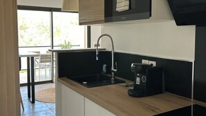 A modern kitchen with a wooden countertop, black appliances, and a large window.