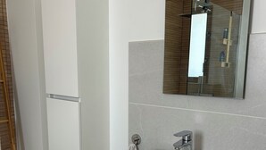 A modern bathroom with a white sink, wooden countertop, and a mirror above it.