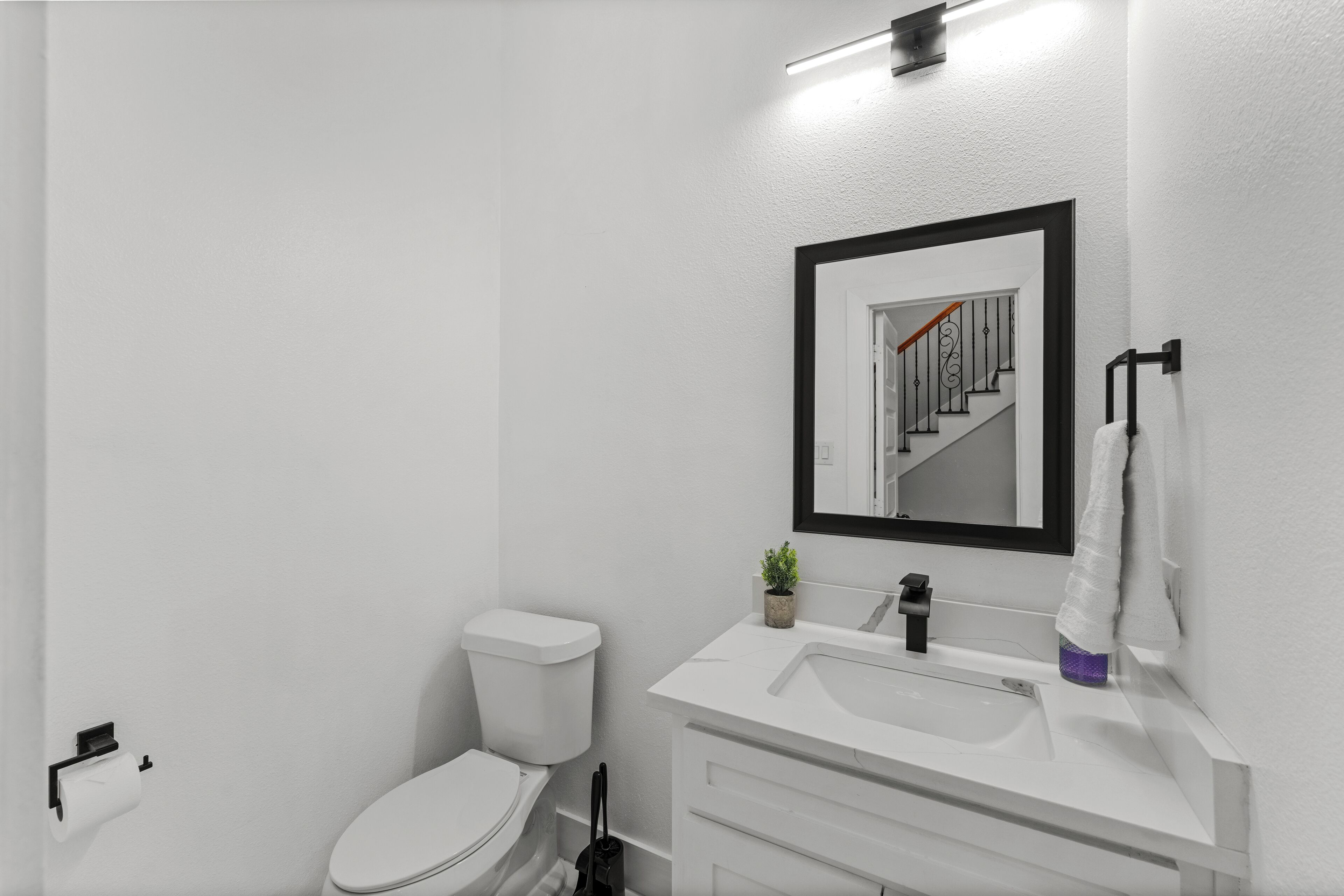 A modern bathroom with a white sink, mirror, and toilet.