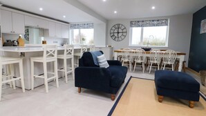 Une cuisine moderne avec des meubles blancs et un coin repas comprenant des chaises et une table, le tout dans des tons blancs.