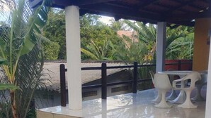 A swimming pool with a covered patio area, white chairs, and tropical plants. - Pousada Sol de Maria (Tibau do Sul)