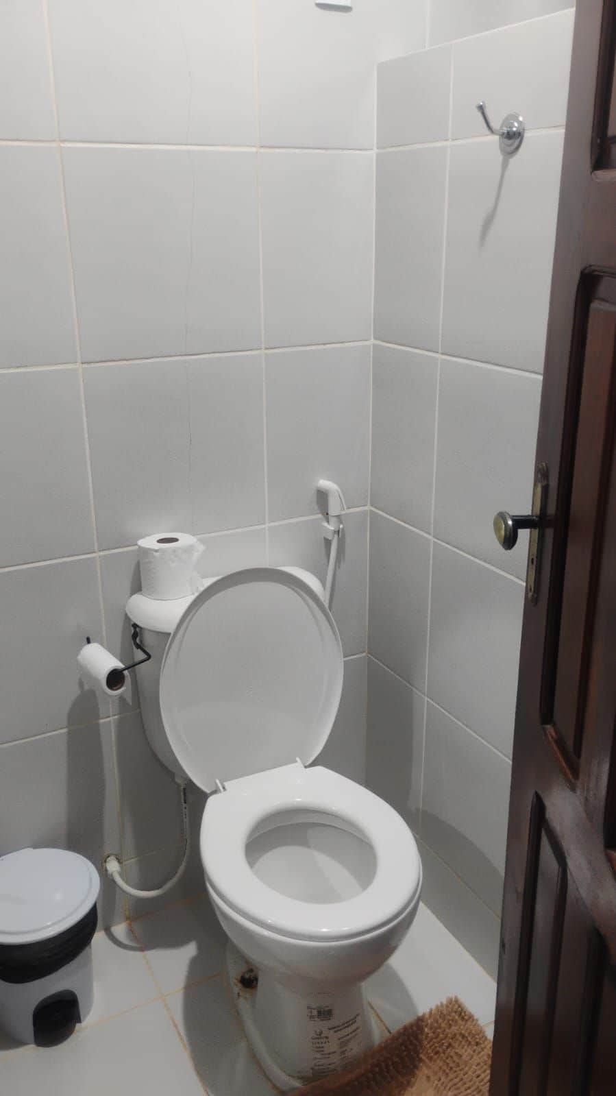 A bathroom with a toilet, bidet, and trash bin.