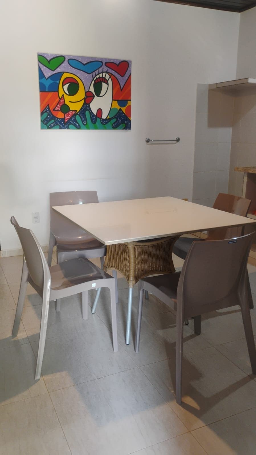 A dining area with a white table, six chairs, and a colorful abstract painting on the wall.