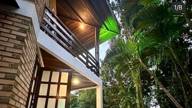 Een modern huis met een bakstenen gevel, een houten balkon en een zwembad.