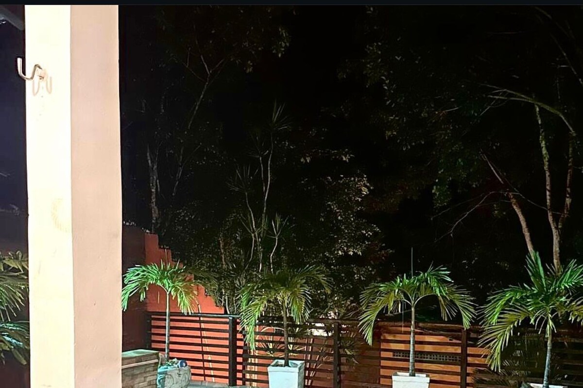 Una piscina con borde de baldosas, rodeada de plantas en macetas y una valla de madera.
