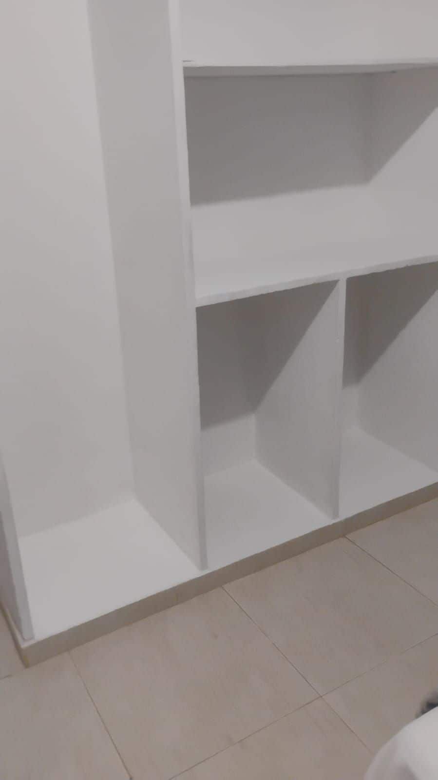 A white, empty room with a tiled floor and a white wall.