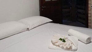A hotel room with a bed, white linens, a wooden door, and a balcony with a view of trees. - Pousada Sol de Maria (Tibau do Sul)