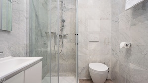 Une salle de bain avec une douche à parois de verre, des toilettes et un lavabo.
