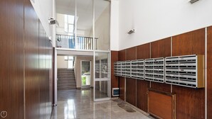 Un intérieur moderne avec un escalier menant à un balcon, une rangée de boîtes aux lettres et un plancher poli.