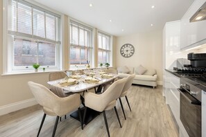 A modern kitchen with a dining area, large windows, and a clock on the wall. - Tottenham Court's Road - 2Bed Apartment (London)