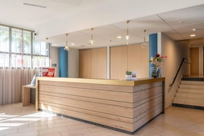 A reception area with a wooden reception desk, pendant lighting, a staircase, and a view of the outdoors.