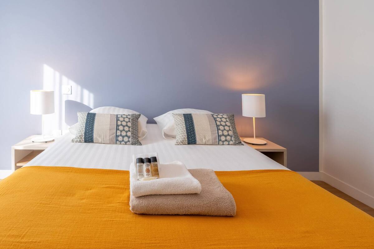 Ein Hotelzimmer mit Bett, zwei Nachttischen, einer Lampe und einem Fenster.
