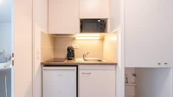 A compact kitchenette with a microwave, coffee maker, sink, and dishwasher.