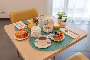 A breakfast table with various food items, a coffee pot, a teapot, and a cup of tea. - Quality Aparthotel Bourgoin-Jallieu (Bourgoin-Jallieu)