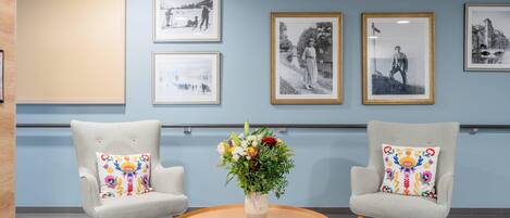Un vestíbulo con dos sillones, una mesa redonda de madera y un florero con flores.