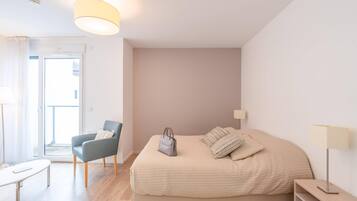 Une chambre à coucher avec un lit, une chaise, une table et une lampe.