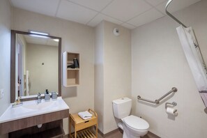 A bathroom with a white sink, mirror, toilet, and shower. - Quality Aparthotel Lyon L'Isle-d’Abeau (L'Isle-d'Abeau)