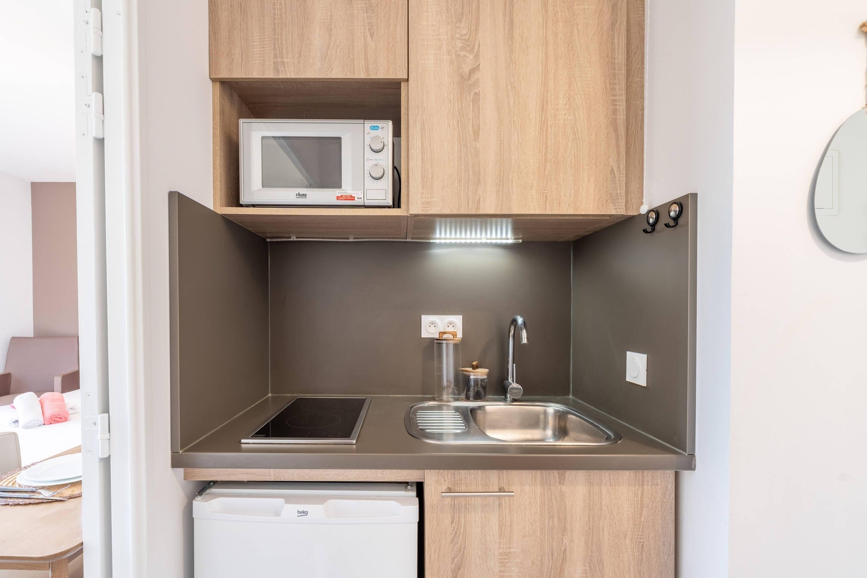 A compact kitchenette with a microwave, sink, and dishwasher.