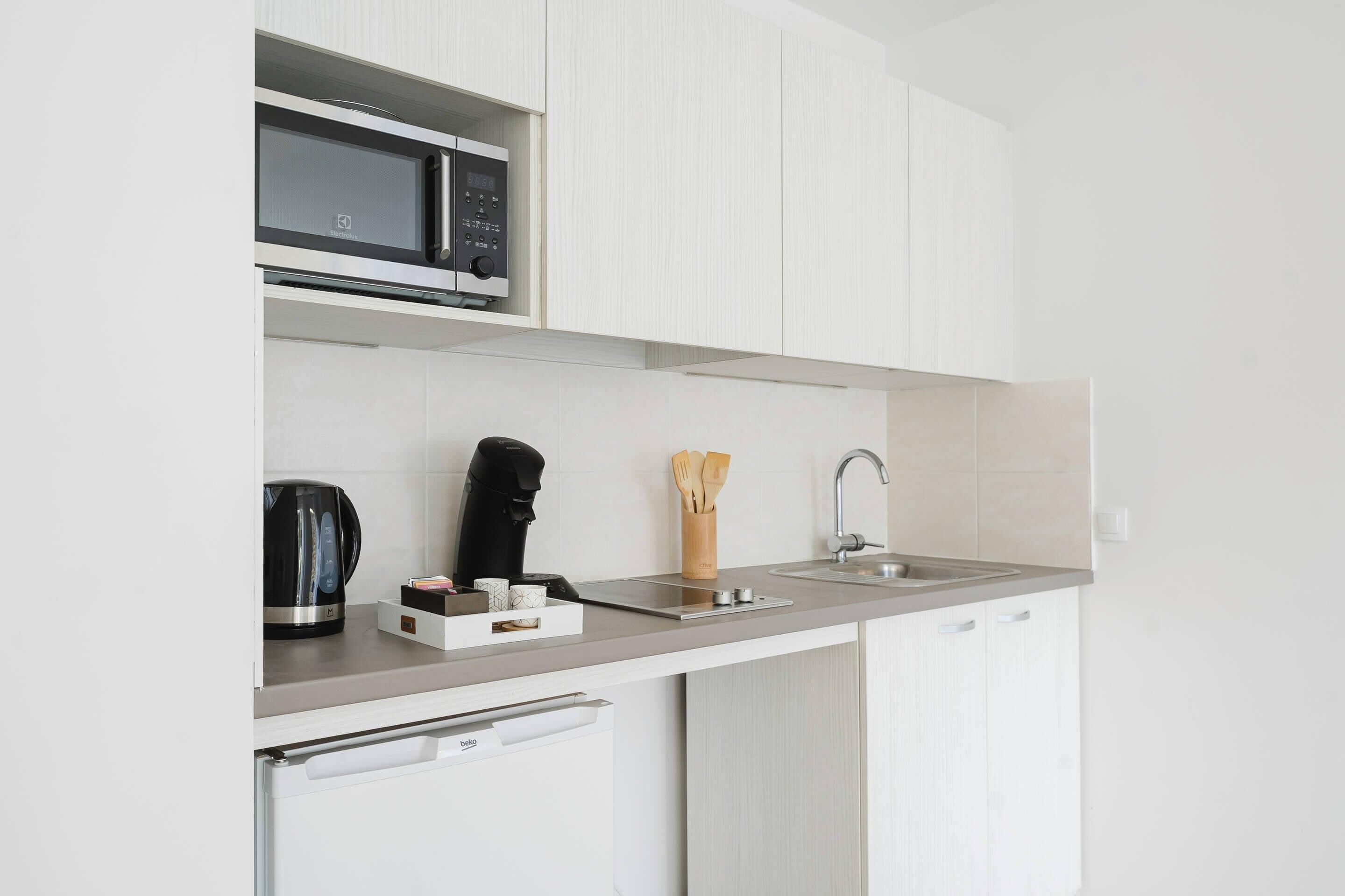 A modern kitchen with a built-in microwave, a coffee maker, a knife block, and a sink.