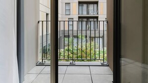 Blick vom Balkon mit Metallgeländer auf ein Mehrstöckiges Gebäude mit Balkonen.