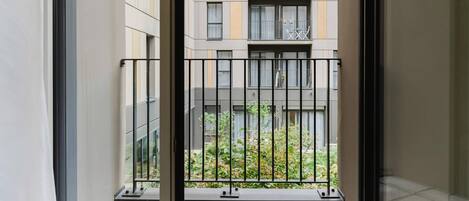 A view from a balcony with a metal railing, looking out at a building with multiple floors and balconies.
