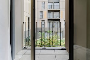 Vista desde un balcón con barandilla metálica, que muestra un edificio de varios pisos y balcones.